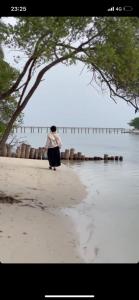 a woman standing on a beach near the water at Rihiveli Inn in Veymandoo