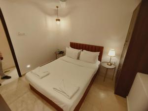 The Majlis Hotel - Colaba Mumbai في مومباي: غرفة نوم صغيرة مع سرير مع ملاءات ووسائد بيضاء