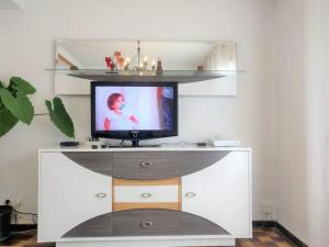 a tv sitting on a white entertainment center with a shelf at Le clos Fleuri in Lescar