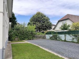 a driveway leading to a house with a fence at Le clos Fleuri in Lescar