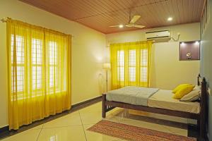 1 dormitorio con 1 cama con cortinas y ventanas amarillas en ORANGE VALLEY TOWN RESIDENCY, en Trivandrum