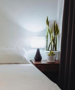 una cama con una lámpara y plantas en una mesita de noche en The Brookside Cottage Sta Magdalena Sorsogon 