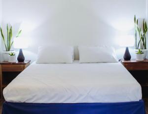 Una cama con sábanas blancas y almohadas en un dormitorio en The Brookside Cottage Sta Magdalena Sorsogon 