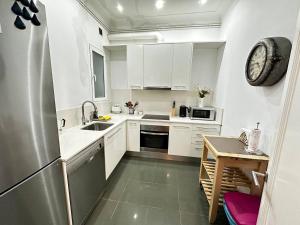 cocina con armarios blancos y nevera de acero inoxidable en Rooms Gran Via, en Barcelona