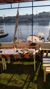 a picnic table in front of the water with a boat at Onaty Narty Guest house in Aswan