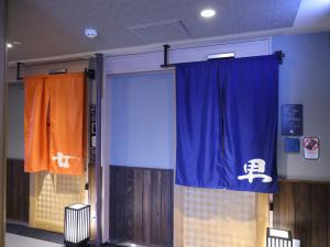 una puerta en una habitación con una cortina y una puerta con una puerta en Dormy Inn Ueno Okachimachi, en Tokio