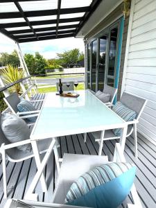 - une table et des chaises blanches sur une terrasse couverte dans l'établissement Mango at the Lake sleeps 8, à Mangakino
