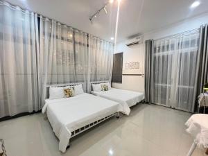 two beds in a room with white walls and windows at BeachSide House Mui Ne II in Ấp Khánh Phước (1)