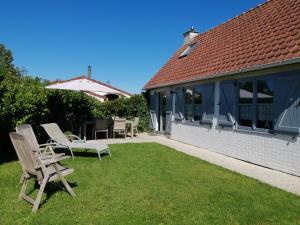 a patio with two chairs and an umbrella on the grass at Vakantienestje in Bredene