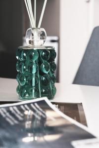 un vaso verde seduto su un tavolo con una rivista di ComeCasa 2 bedrooms Larga apartment a Milano