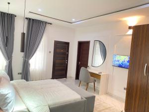 a bedroom with a bed and a desk and a television at Luxe Haven Lekki in Lekki