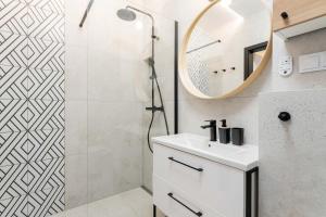 a bathroom with a white sink and a mirror at Maple Tree Premium Apartment Mokotow in Warsaw
