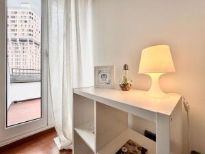 un tavolo bianco con una lampada sopra accanto a una finestra di ComeCasa 2 bedrooms Larga apartment a Milano