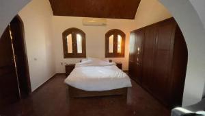 a bedroom with a white bed and two windows at NubaNile Guesthouse in Shellal