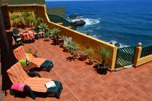 un balcón con sillas, mesas y el océano en Casa Rural Virgen del Rosario en San Juan de la Rambla