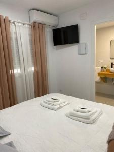 Una cama blanca con dos toallas encima. en Apartamento Baeza 4B, en Baeza