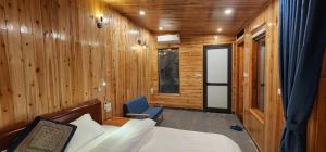 - une chambre avec un lit, une chaise et des murs en bois dans l'établissement Huy Trung Homestay, à Bắc Hà