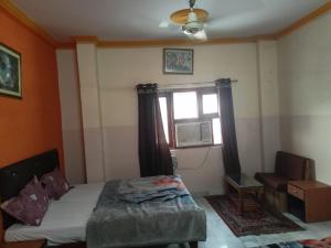 a bedroom with a bed and a window and a chair at Stephels Hostel in Jaipur