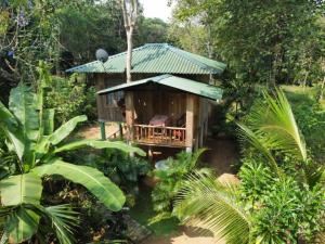 un petit bâtiment avec un toit vert dans une forêt dans l'établissement Ruk Sewana Villa Tree House, à Sigirîya