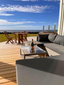 - une terrasse avec un canapé et une table avec une bouteille de vin dans l'établissement Oceanfront & Aurora Dreamscape Villa, à Álftanes