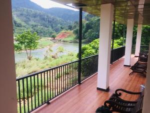 een balkon met stoelen en uitzicht op een rivier bij VRK Adventure Base Camp in Kitulgala