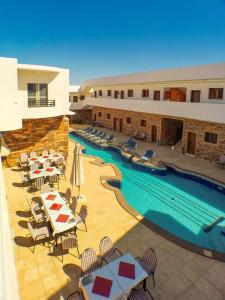 un complejo con piscina y sillas y un hotel en Carmine Hotel Dahab en Dahab