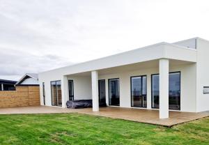 Cette maison blanche dispose de grandes fenêtres. dans l'établissement Oceanfront & Aurora Dreamscape Villa, à Álftanes