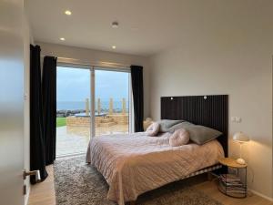 - une chambre avec un lit et une grande fenêtre dans l'établissement Oceanfront & Aurora Dreamscape Villa, à Álftanes