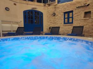 a large swimming pool with blue water in a building at Margerita Farmhouse in Qrendi
