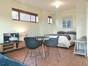a bedroom with a bed and two chairs and a table at Loft Cottage, sleeps 2. Central and Cozy! in Cape Town