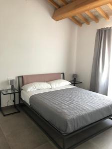 un letto in una camera bianca con due tavolini di B&B Il Passo a Urbino