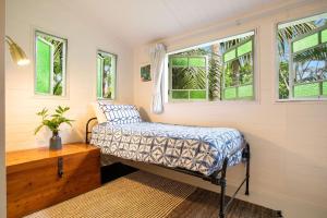 a small bedroom with a bed and two windows at Coco's Cottage in the Byron Bay Hinterland in Bangalow