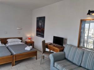 sypialnia z łóżkiem, biurkiem i kanapą w obiekcie Pantheon Apartments Kos Town w mieście Kos