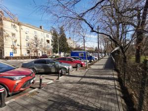 a row of parked cars on a city street at ALDIRA Studio Arena Nationala in Bucharest