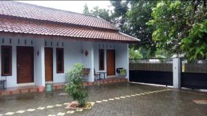 a small white house with a fence and a patio at Umah isun guests house in Banyuwangi
