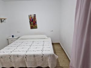 1 dormitorio blanco con 1 cama con manta blanca en Cortijo barranco higuera 2, en Fernán Pérez