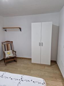 Fernán PérezにあるCortijo barranco higuera 2の白いキャビネットと椅子付きのベッドルーム1室