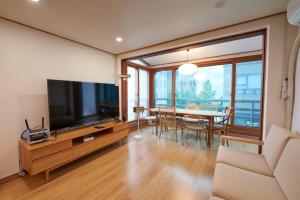 un soggiorno con TV e tavolo con sedie di Mapo Villa in Shinchon a Seul