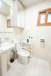 a white bathroom with a toilet and a sink at Mapo Villa in Shinchon in Seoul