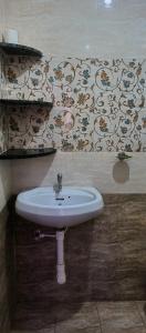 a white sink in a bathroom with wallpaper at Sobitai in Palolem
