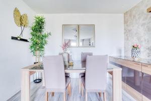 une salle à manger avec une table en verre et des chaises blanches dans l'établissement Le Warm Cocon - spacieux T3 - 5 personnes - wifi et parking, à Rosny-sous-Bois 12 autres photos