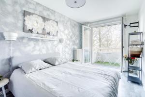une chambre blanche avec un grand lit et une fenêtre dans l'établissement Le Warm Cocon - spacieux T3 - 5 personnes - wifi et parking, à Rosny-sous-Bois