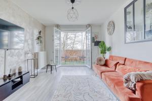 - un salon avec un canapé orange et une table dans l'établissement Le Warm Cocon - spacieux T3 - 5 personnes - wifi et parking, à Rosny-sous-Bois