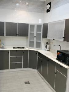 eine Küche mit grauen und weißen Schränken und einer Mikrowelle in der Unterkunft فلل الكناري الراقية in Ta'if