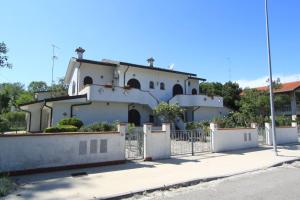 a white house with a fence in front of it at Appennini Villas in Lido di Pomposa