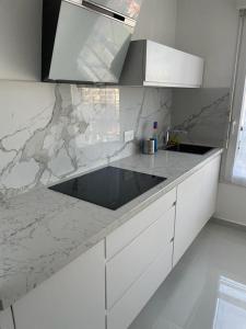 cocina con encimera de mármol y armarios blancos en Apparemment colombes, en Colombes