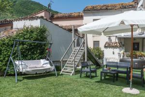 eine Hängematte und Stühle im Garten mit Sonnenschirm in der Unterkunft La Casa dei Nonni in Isola del Gran Sasso dʼItalia