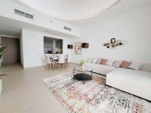 a white living room with a white couch and a table at Luxury cozy apartment Al jda in Sharjah