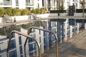 a swimming pool with two chairs next to a building at Luxury cozy apartment Al jda in Sharjah