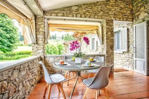 eine Terrasse mit einem Tisch, Stühlen und einer Steinmauer in der Unterkunft Villa Giuliana in Arezzo